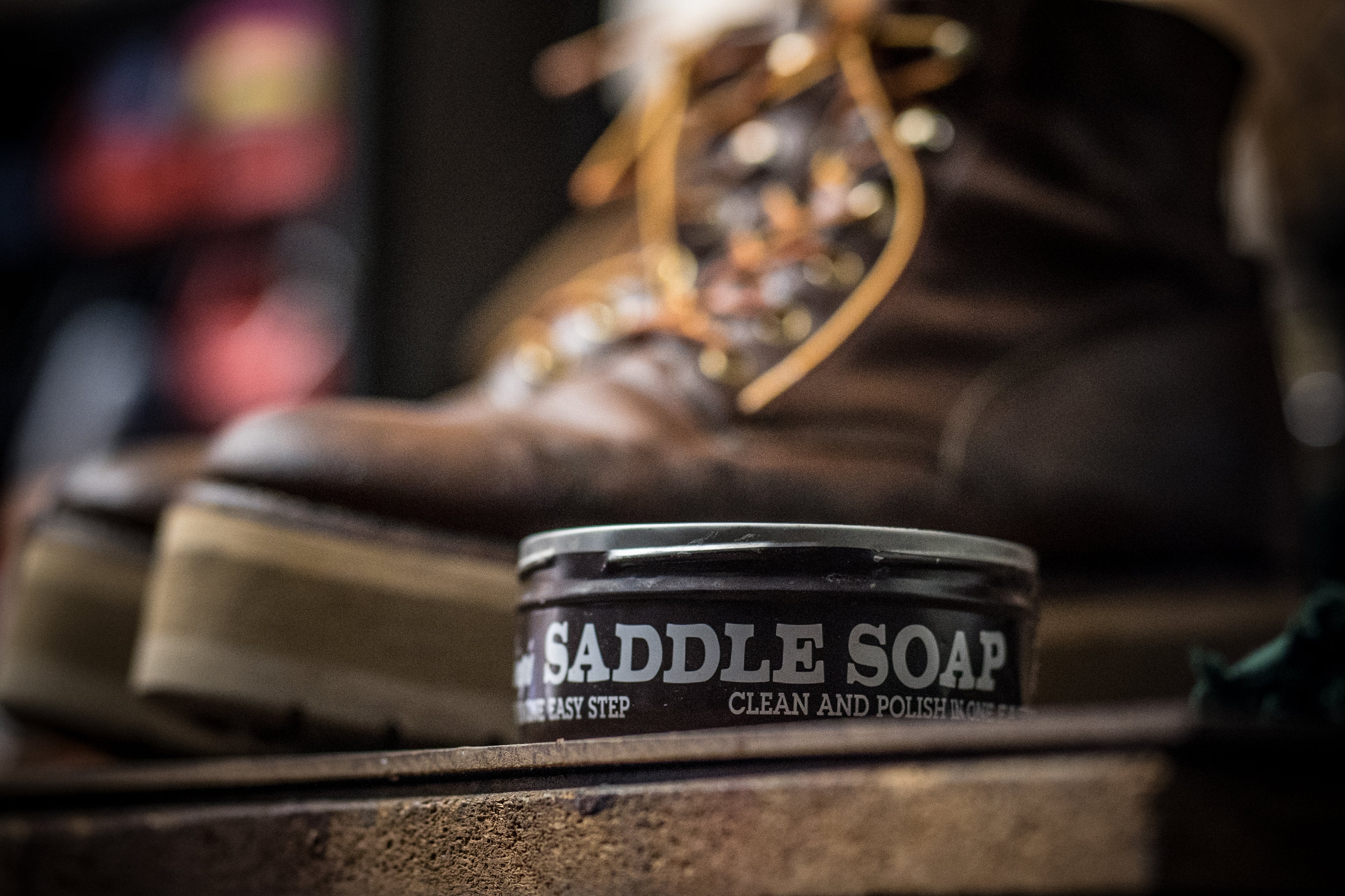 Saddle soap container with a blurred background of a boot