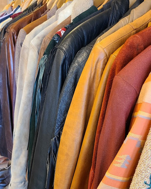 Row of various leather jackets displayed on a rack.